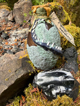 Load image into Gallery viewer, Back view of gray-green mottled dragon egg showing spiked tail wrap and heavy crater texture