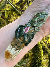 Load image into Gallery viewer, leaf patterned magic wand on driftwood, with daisy inside a resin crystal on it, laying on a person's hand