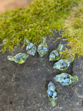 Load image into Gallery viewer, 7 clear resin bird figures with forget me not flowers and moss inside, all sitting in a semi circle on a mossy stone