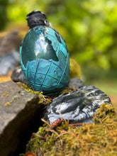 Load image into Gallery viewer, Teal gradient dragon egg with black spikes and color-changing teal highlights, clear liquid settled, skeleton key charm
