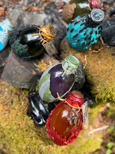 Load image into Gallery viewer, Dragon egg potion bottle collection displayed at mossy stone firepit, angle four
