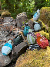 Load image into Gallery viewer, Dragon egg potion bottle collection displayed at mossy stone firepit, angle three
