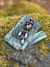 Load image into Gallery viewer, Sculpted polymer forest brooch with purple polka dotted mushrooms on a miniature stump environment, same style mushrooms dangling on bronze chain with added bronze bell. Made by The Woodland Wandolier, photographed on a mossy grey boulder
