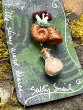 Load image into Gallery viewer, Hand sculpted peachy bronze snail shell with mushroom colony on its back, with a tiny round bottle of salt dangling below it via brass findings.made by The Woodland Wandolier 

