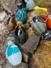 Load image into Gallery viewer, Dragon egg potion bottle collection at mossy stone firepit from varying angle
