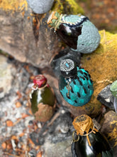 Load image into Gallery viewer, Dragon egg potion bottle collection displayed at mossy stone firepit, angle five
