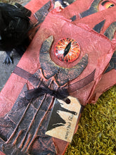 Load image into Gallery viewer, Close up of Handmade rust-colored notebook with a unique black tower design, featuring a prominent red glass eye reminiscent of Sauron from LOTR
