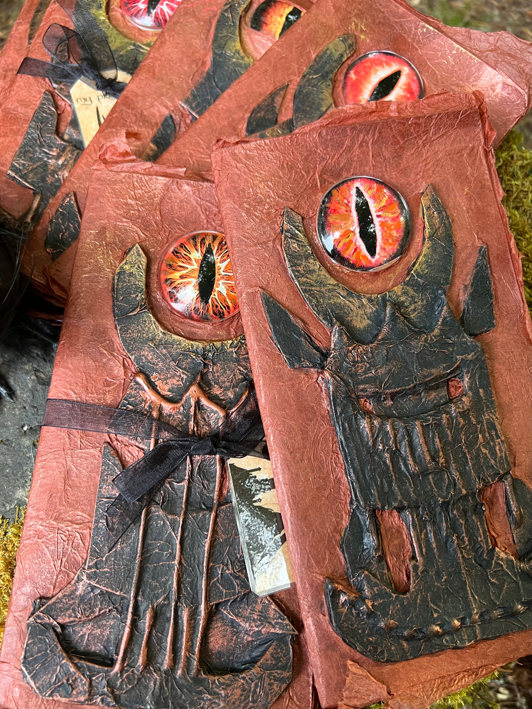 Handmade rust-colored notebook with a unique black tower design, featuring a prominent red glass eye reminiscent of Sauron from LOTR. 